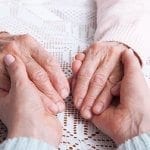 Older hands hold younger hands. Nursing home abuse concept photo.