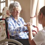 an older woman in a wheelchair smiles at a younger woman