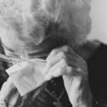 An older woman wipes her eye after crying