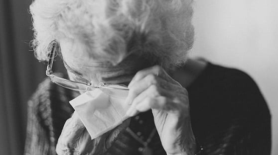 An older woman wipes her eye after crying