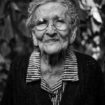 A sad elderly woman with glasses.