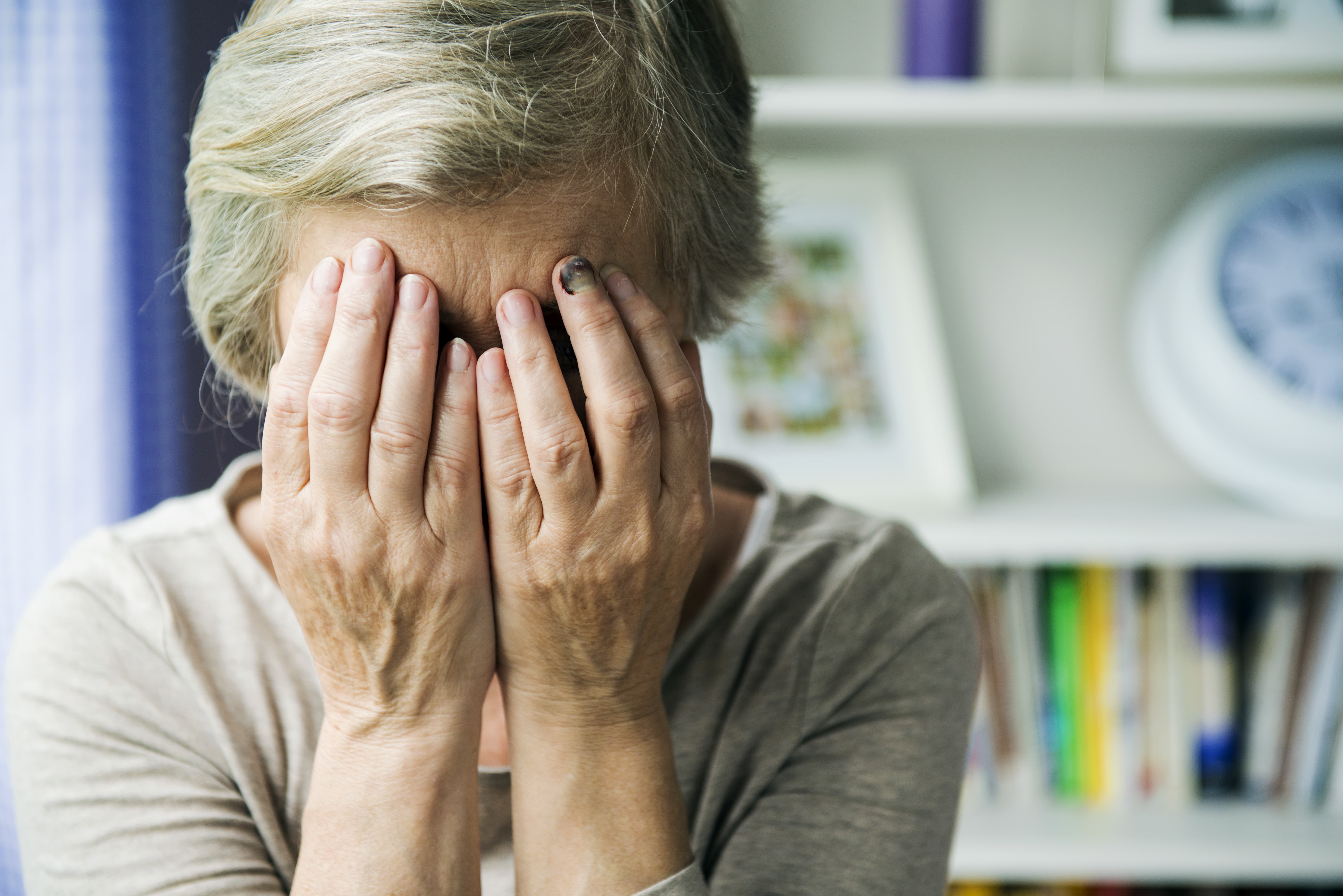 An old woman holds her head in her hands
