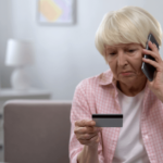 elderly woman looking at credit card and talking on the phone