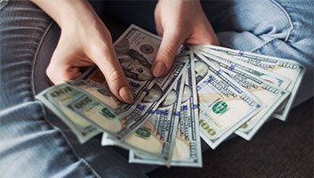 close up of woman holding several $100 bills