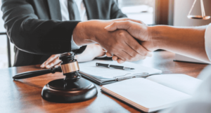 Handshake between a nursing home lawyer and client at a desk with gavel, papers, and legal documents.