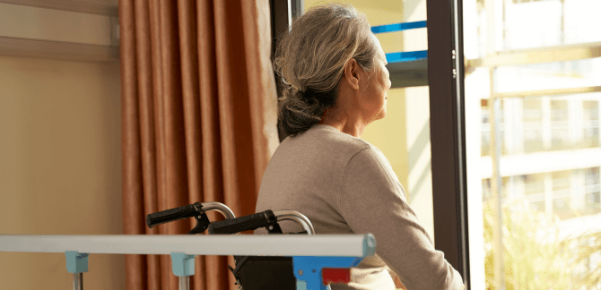 Elder in wheelchair looking out a window
