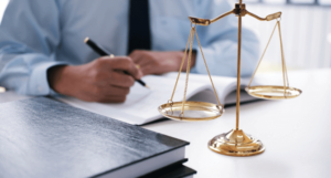 A nursing home abuse lawyer writes notes at a desk beside golden scales of justice.