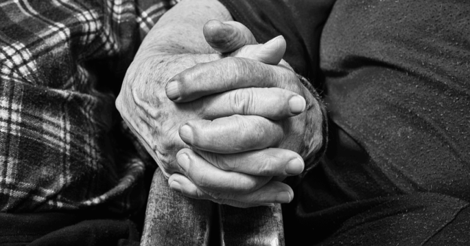 Elderly couple holding hands on chair