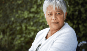 An older adult in a wheelchair, looking worried, raising concerns about elder abuse.