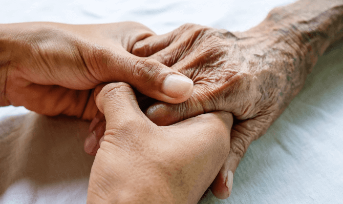a younger person holds the hand of an older person