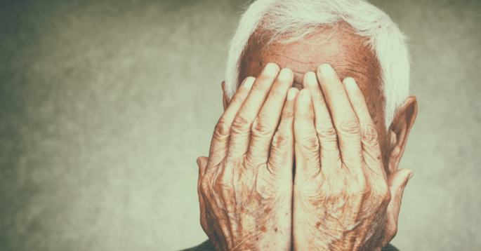 a sad older man with his head in his hands