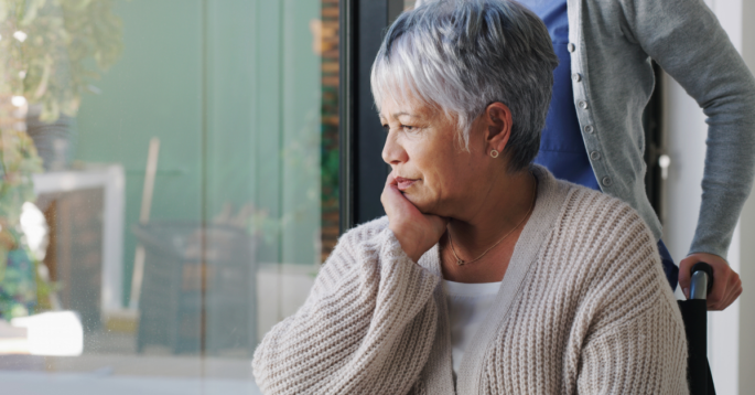 Woman sits with hand on chin while looking out a window