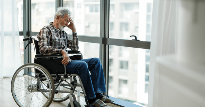 Nursing home resident sits alone at window