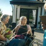 A nursing home administrator talks to two residents next to a majestic view of the mountains.