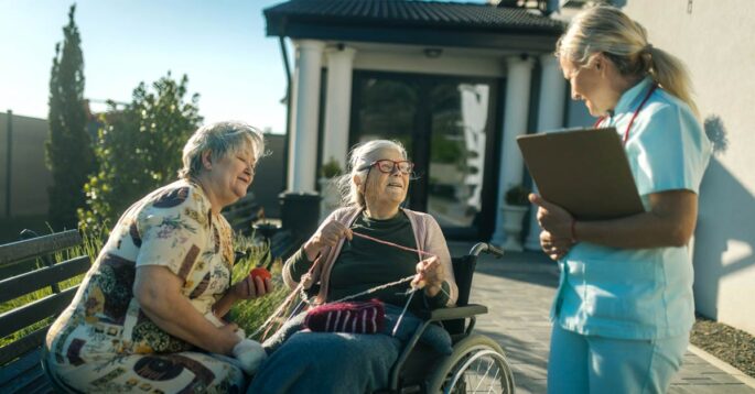 A nursing home administrator talks to two residents next to a majestic view of the mountains.