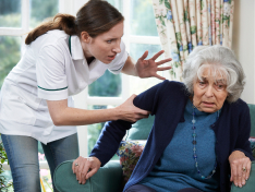 A caregiver tightly gripping an older woman's arm as she looks visibly frightened, showing nursing home abuse.