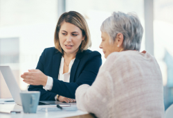 A lawyer discusses a potential nursing home settlement amount with a client at her laptop in an office.